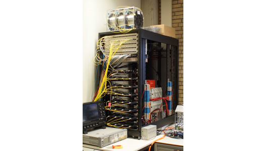 Figure 1. Timing System Setup in Amsterdam. It consists of several White Rabbit Switches from Seven Solutions (top panels in the rack), a copper ethernet switch, an Arbiter 1084B GPS, 32x ZEN-CTA boards (four in each of the lower panels of the rack) and several kilometers of single-mode optical fibers (e.g., on top of the rack). Image credit: Heike Prokoph. Figure 1. Timing System Setup in Amsterdam. It consists of several White Rabbit Switches from Seven Solutions (top panels in the rack), a copper ethernet switch, an Arbiter 1084B GPS, 32x ZEN-CTA boards (four in each of the lower panels of the rack) and several kilometers of single-mode optical fibers (e.g., on top of the rack). Image credit: Heike Prokoph.